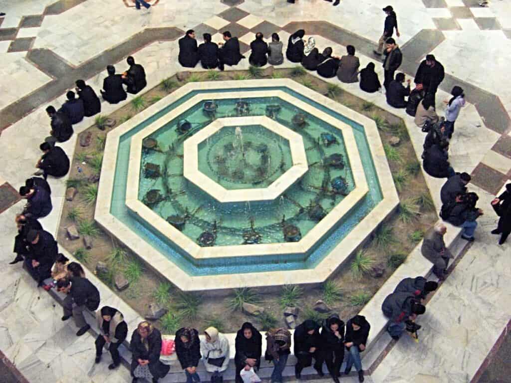 people sitting around a fountain a shopping mall in Tehran