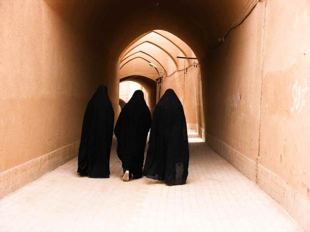Iranian women walking in chador in the mud-brick alleys
