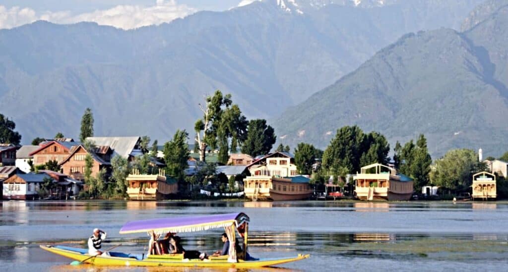 Houseboats anchored in the Dal lake with Shikara boats and snowcapped mountains in the backround