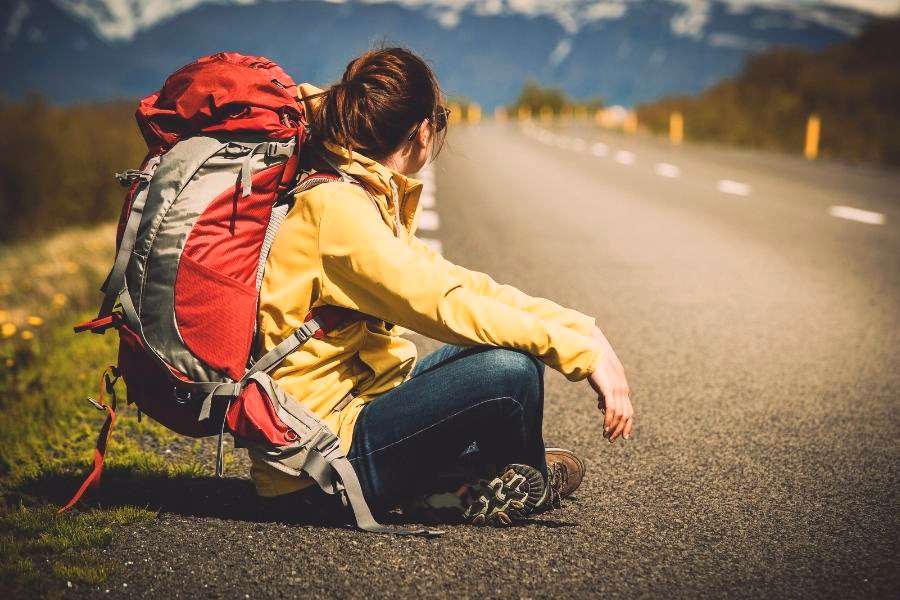 A backpacker sitting along the empty road
