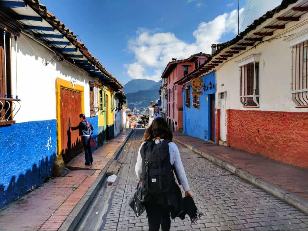 There are several reasons why is traveling is important, tourist walking among colorful houses in Colombia